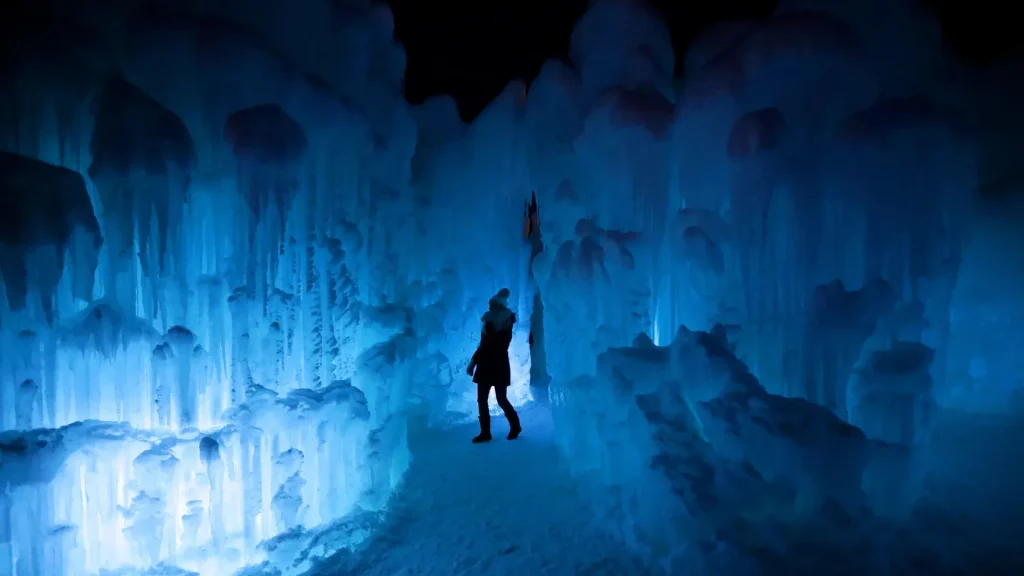 An image from the Ice Caves in Lake Geneva as a person stands on the trail. Lights create a glow within the dark cave.