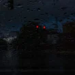 A photo from the inside of a vehicle on a dark rainy night as it stop at a red light.