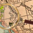 A map of North America zoomed in on the west coast of the United States as a gold magnifying glass hovers over the west coast. Several icons are positioned over the map representing big foot, the thunderbird, nightcrawlers, and the chupacabra.