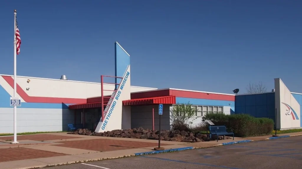 The exterior of the Greyhound Bus Museum sits on a clear blue sky day and is red, white, and blue.