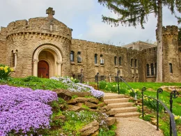 Springtime at Bishop Simon Brute College, Indiana. A historic castle with intricate Christian details amid vibrant gardens.