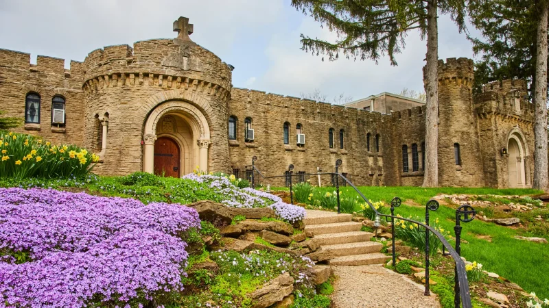 Springtime at Bishop Simon Brute College, Indiana. A historic castle with intricate Christian details amid vibrant gardens.