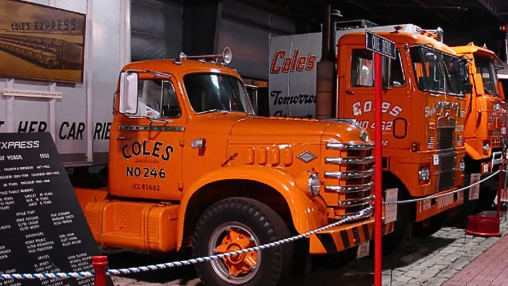 An orange truck from inside the Cole Land Transportation Museum. The truck sits beside a row of other trucks with "Cole's" printed on the sides.