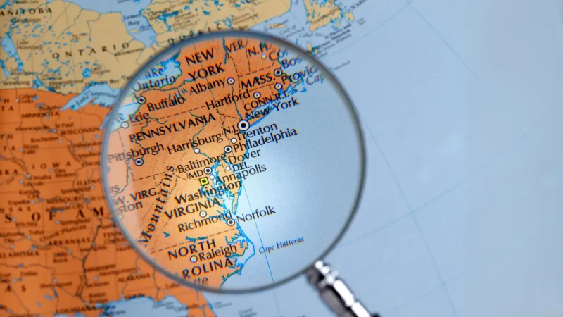 A map showcasing the Eastern coast of the United States with a magnifying glass being held over it.