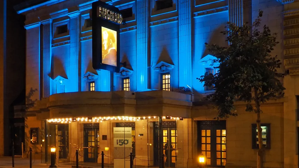 The exterior of the Fitzgerald Theater at night, lit up from the outside with amber and blue lights.