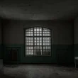 A dark room in an abandoned building with large windows sits nearly empty.