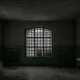 A dark room in an abandoned building with large windows sits nearly empty.