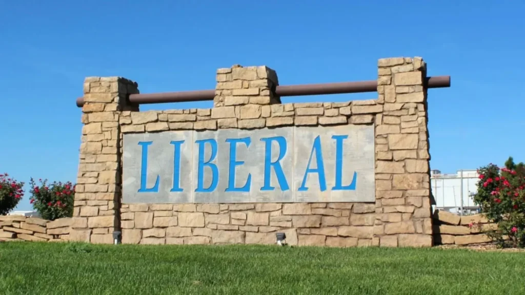 The Liberal city sign is made of stone with the word "LIBERAL" painted in blue serifed letters.