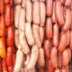 Strings of different types of sausages hanging side-by-side ranging in colors of red, orange, and pinks.