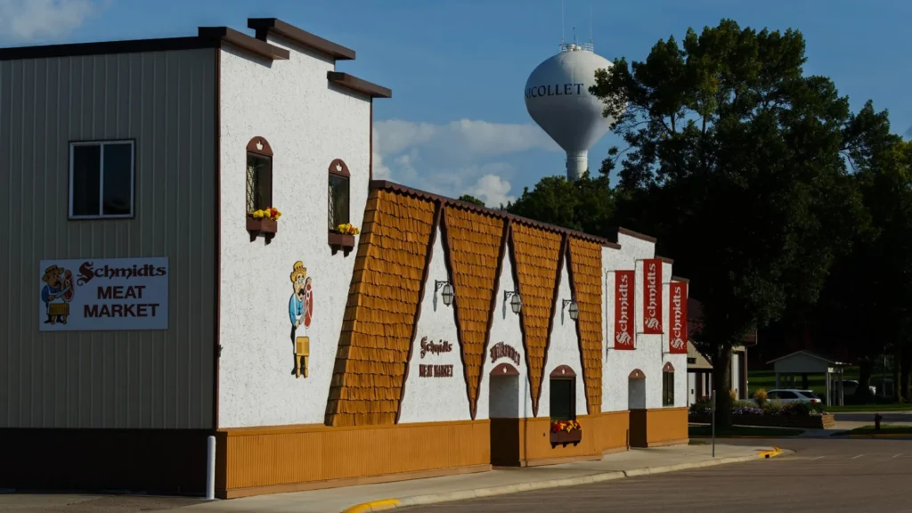 A photograph of the outside of Schmidt’s Meat Market in the style of an older German building. In the background is the Nicollet water tower.